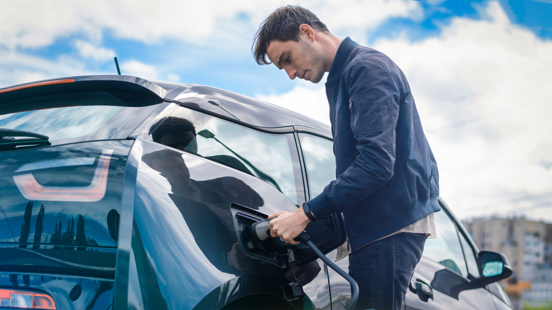 A man connects a charging cable to his electric vehicle.